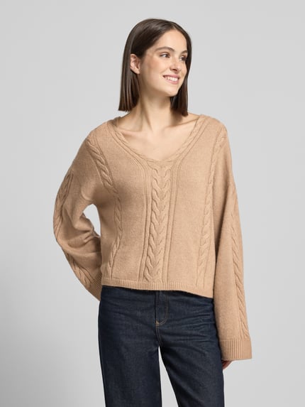 Frauenmodel trägt Pullover aus Schurwolle mit Zopfmuster von BOSS Orange, unifarben, Regular Fit, Cropped, V-Ausschnitt, Strick, Ganzkörperansicht von vorne.