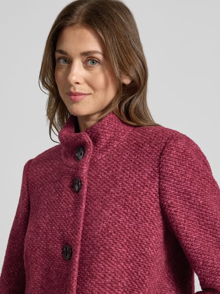 Frauenmodel trägt Jacke mit Stehkragen Modell 'JANINE' von Milo Coats in dunklem Beerenrot, strukturierte Oberfläche, Nahaufnahme Oberkörper. Material-Mix mit Schurwolle-Anteil, Slim Fit, Knopfverschluss, Eingrifftaschen.