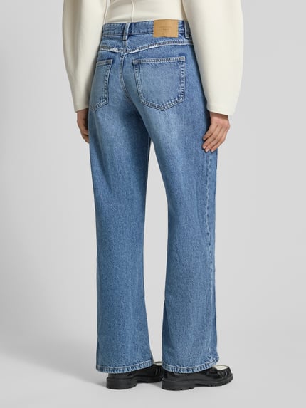 Frauenmodel trägt Wide Leg Jeans mit Fransennähten von Gina Tricot aus Reine Baumwolle, blauer Jeans-Stoff mit Gesäßtaschen, Wide-Fit, Ganzkörperansicht Rückansicht.