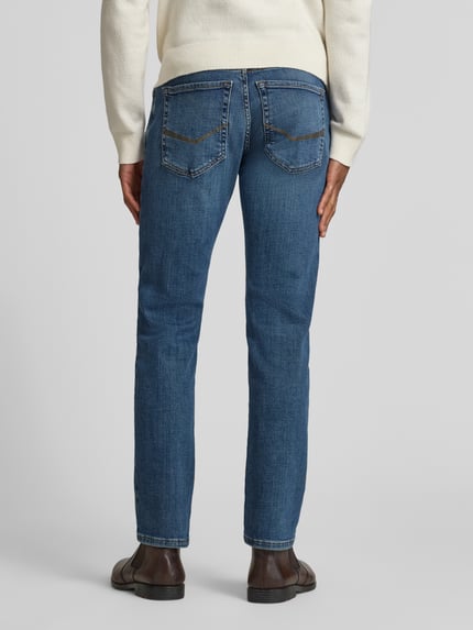 Męski model nosi Tapered Fit Jeansy z 5 kieszeniami Model 'Lyon' od Pierre Cardin, mieszanka bawełny ze stretchem, widok całej sylwetki z tyłu. Szerokość w pasie 42 cm, długość wewnętrznej nogawki 80 cm.