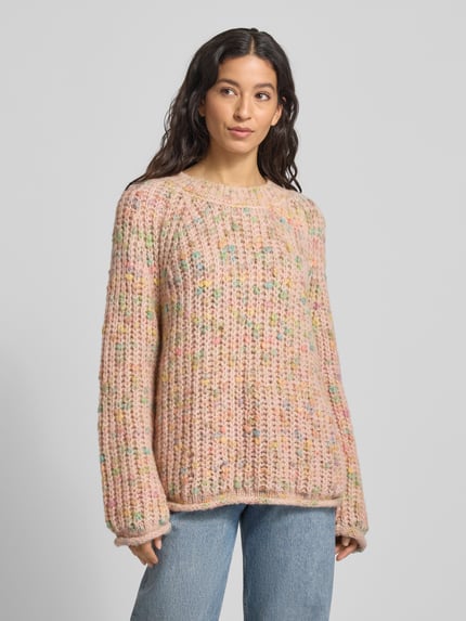 Modelka kobieca nosi Strickpullover mit Rundhalsausschnitt und Rollsaum od Smith and Soul, regular fit, różowy grobstrick, efekt przędzy, widok całej sylwetki z przodu.