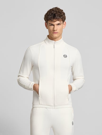 Męską model nosi Slim Fit Tracksuit mit Logo-Stitching model 'Egeo' od SERGIO TACCHINI z mieszanki bawełny, krój slim fit, stójka, zamek błyskawiczny, elastyczne wykończenia, jasny kolor, gładka tekstura, szerokość w rozmiarze M: 42 cm, długość tyłu w rozmiarze M: 64 cm, szerokość ramion w rozmiarze M: 46 cm, długość rękawów w rozmiarze M: 67 cm, długość wewnętrzna nogawki w rozmiarze M: 73 cm, wyhaftowane logo, całkowity widok z przodu.