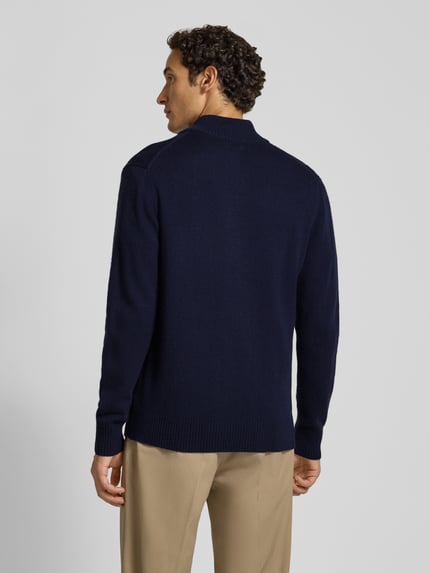 Männermodel trägt Strickpullover aus reiner Lammwolle mit Logo-Patch Modell 'Tay' von Wood Wood, marineblau, Regular Fit, Rückansicht, Ganzkörperansicht Rückansicht.