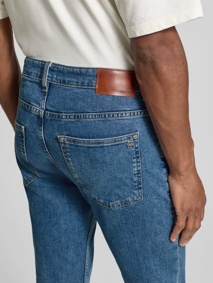 Mannelijk model draagt Slim Fit Jeans uit katoenmix model 'DELAWARE' van BOSS Orange, melange denim met label patch, Ganzkörperansicht Rückansicht.