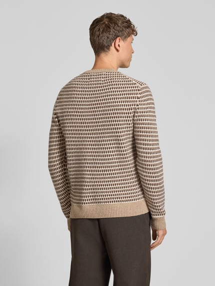Männermodel trägt Pullover aus Wolle mit Strukturstrick von GANT in mehrfarbiger Strickoptik, Rippstrickdetails, Ganzkörperansicht Rückansicht.