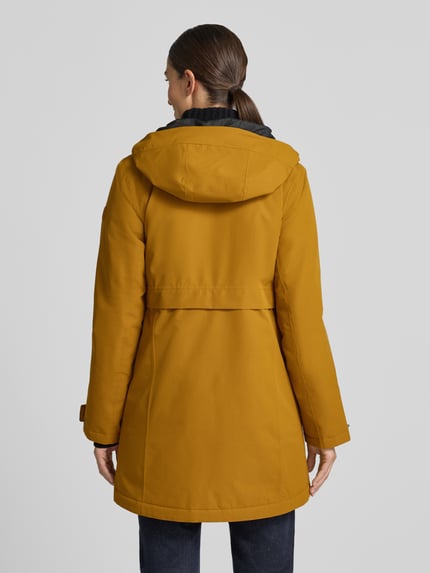 Frauenmodel trägt Regular Fit Parka mit Kapuze von Didriksons in Senfgelb, strukturierte Oberfläche, Zweiwege-Reißverschluss, Ganzkörperansicht Rückansicht, Damen Parka, Kapuze, Eingrifftaschen, Rückenlänge 87 cm, Schulterbreite 41 cm, Brustweite 48 cm, Ärmellänge 55 cm.