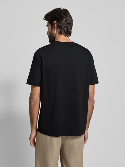 Männermodel trägt T-Shirt mit Label-Detail Modell 'Achilleas' von JOOP! Collection, schwarze Reine Baumwolle, Regular-Fit, Ganzkörperansicht Rückansicht.