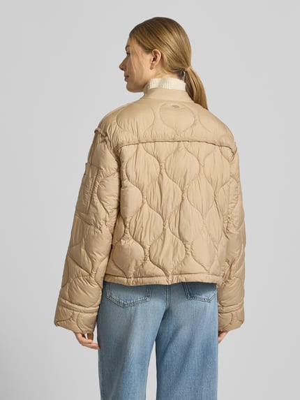Modelka prezentuje kurtkę pikowaną z zamkiem błyskawicznym dwustronnym model 'IMANE' od Beaumont Amsterdam, krój relaxed fit, stójka, tył w rozmiarze 36: długość 55 cm, szerokość ramion 44 cm, szerokość klatki piersiowej 60 cm, długość rękawów 61 cm, beż, tekstura pikowania, całkowity widok sylwetki z tyłu