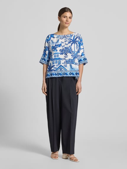 Vrouwenmodel draagt Regular Fit Bluse aus Viskose-Mix van Christian Berg Woman, blauwe all-over motiefmix, knoopsluiting, halflange mouwen, ronde hals, ruglengte maat 36: 55 cm, mouwlengte maat 36: 30 cm, geheel lichaamsaanzicht van voren.