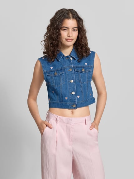 Frauenmodel trägt Regular Fit Jeansweste mit Motiv-Print Modell 'VEGA' von Only in Denim-Optik mit Umlegekragen, Knopfleiste, Label-Applikation, Brusttaschen, reine Baumwolle, mittleres Blau, Strukturmix, Ganzkörperansicht von vorne.