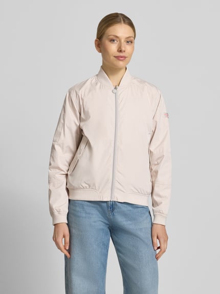 Frauenmodel trägt Regular Fit Bomberjacke mit Stehkragen Modell 'Brooklyn' von Frieda & Freddies in hellem Beige mit Reißverschluss, Eingrifftaschen und elastischen Abschlüssen, kombiniert zu hellblauer Jeans, Ganzkörperansicht von vorne. Rückenlänge bei Größe 36: 59 cm, Schulterbreite: 44 cm, Brustweite: 52 cm, Ärmellänge: 51 cm.