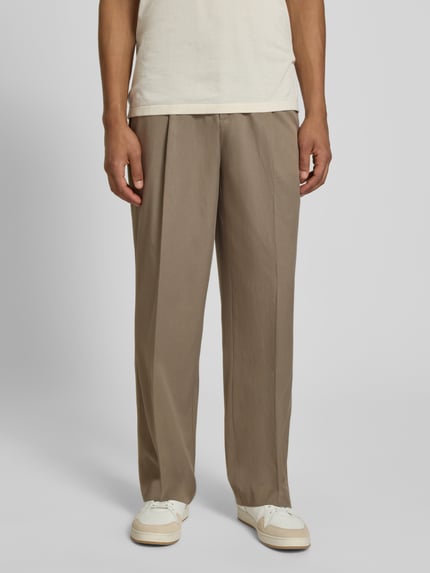 Männermodel trägt Hose mit Bügelfalten Modell 'Reece' von Les Deux in Beige, regular Fit, glatte Textur, Ganzkörperansicht von vorne.