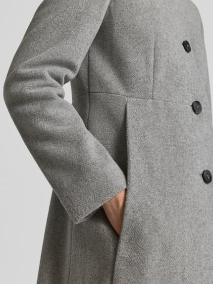 Frauenmodel trägt Regular Fit Mantel aus Woll-Mix von FUCHS SCHMITT in Hellgrau mit Knopfleiste und Stehkragen, Nahaufnahme Oberkörper. Rückenlänge 84 cm, Schulterbreite 41 cm, Brustweite 47 cm, Ärmellänge 67 cm.