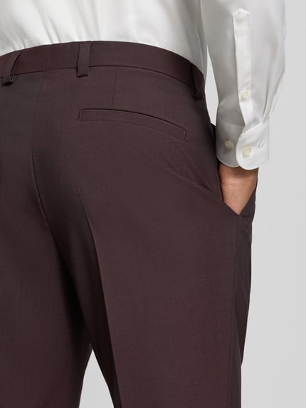 Männermodel trägt Regular Waist Business-Hose aus Schurwolle mit Bundfalte von HUGO, unifarben, glatte Textur, Nahaufnahme Hüfte, seitliche Eingrifftaschen, Gesäßtaschen, Bügelfalten, Gürtelschlaufen, Verschluss mit Schiebehaken und verdecktem Reißverschluss.