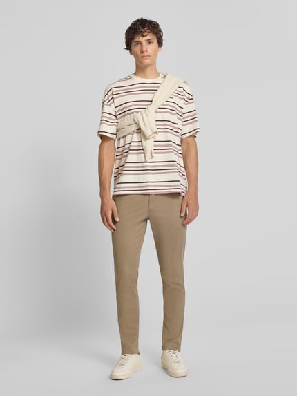 Męski model nosi spodnie Slim Fit Hose mit Gesäßtaschen Modell 'MARCO' von Jack & Jones, mieszanka bawełny i elastanu, beżowy, krój slim fit, kieszenie z tyłu, Szerokość w rozmiarze 32/32: 43 cm, Długość wewnętrzna nogawki w rozmiarze 32/32: 77 cm, Ganzkörperansicht von vorne.