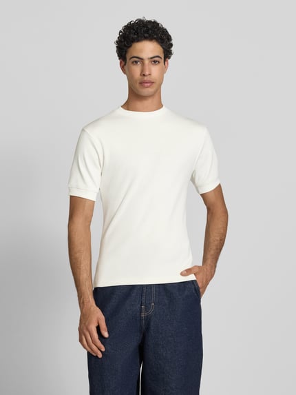 Männermodel trägt Slim Fit T-Shirt mit Label-Stitching von PROHIBITED aus Baumwoll-Elasthan-Mix in Weiß, Herren T-Shirt, Ganzkörperansicht von vorne. Rückenlänge bei Größe M: 65 cm, Rundhalsausschnitt.
