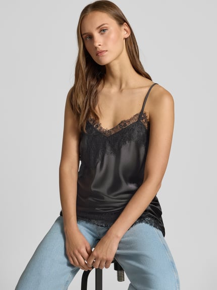 Frauenmodel trägt Regular Fit Blusentop mit Spitzenbesatz Modell 'INDONA' von ONLY in Schwarz, leichte Satin-Textur, Nahaufnahme Oberkörper, Damen Blusentop von ONLY