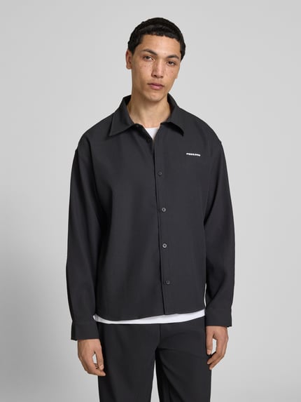 Männermodel trägt Regular Fit Freizeithemd mit Kentkragen und Label-Stitching von Pegador, Material-Mix mit Stretch-Anteil, Nahaufnahme Oberkörper.