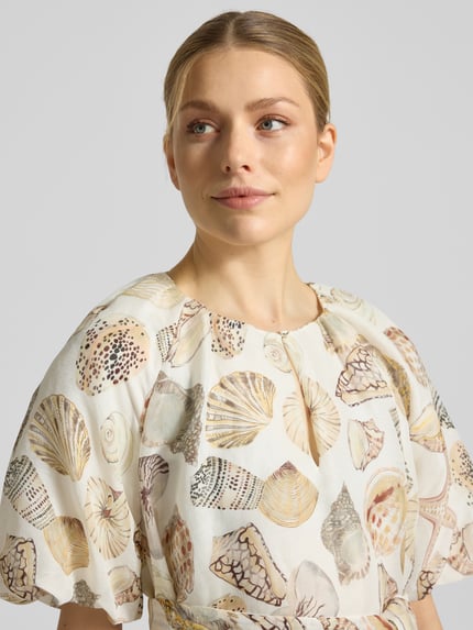 Frauenmodel trägt Knielanges Kleid aus Viskose mit Bindegürtel von Marc Cain im Allover-Look mit Schlüsselloch-Ausschnitt, Nahaufnahme Oberkörper. Reine Viskose, Taillierter Schnitt, Knielänge, Rückenlänge bei Größe 36: 95 cm, Brustweite 52 cm, Ärmellänge 38 cm.