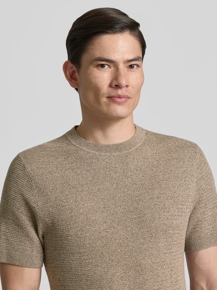 Männermodel trägt Herren Strickshirt mit Rundhalsausschnitt Modell 'RILEY' von Jack & Jones Premium in Beige, Strukturmuster, Nahaufnahme Oberkörper.