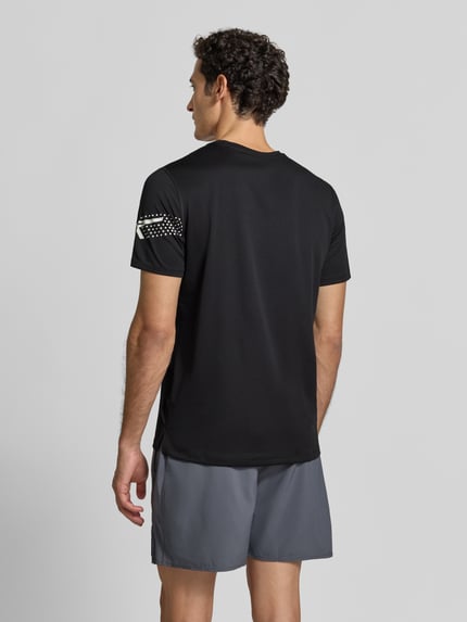 Männermodel trägt Regular fit t-shirt met labelprint Model 'ICON' van ASICS TIGER in zwart, Ronde hals, ruglengte maat M 71 cm, Ganzkörperansicht Rückansicht.