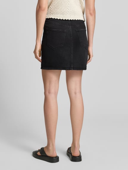 Vrouwenmodel draagt Regular Fit Jeansrok uit katoenmix model 'TESSA' van Vero Moda, denim-look, mini, zwart, vijfzakken, label patch, riemlussen, knoop- en rits, twillmateriaal, detailopname achterkant.