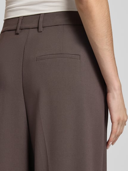 Frauenmodel trägt Anzughose mit Viskose-Anteil von COMMA in Dunkelbraun mit Bundfalte und Gesäßtasche, Detailaufnahme, Relaxed Fit.