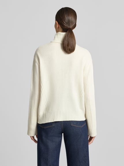 Frauenmodel trägt Relaxed Fit Rollkragenpullover aus reiner Wolle von Liu Jo White in Creme mit Strasssteinen, Ganzkörperansicht Rückansicht.