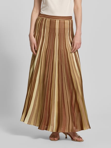 Frauenmodel trägt Maxirock aus Viskose im Allover-Look von Bash in Braun- und Beigetönen, A-Linie, elastischer Bund, Ganzkörperansicht von vorne.