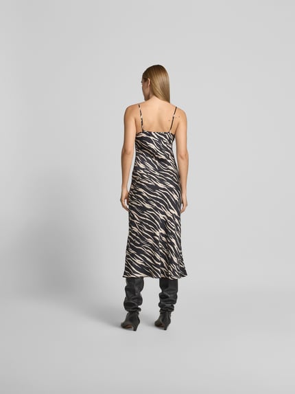 Modelka nosi sukienkę midi z czarno-beżowym wzorem, cienkie ramiączka, krój slim fit, długość midi, wiskoza, Lala Berlin, widok całej sylwetki z tyłu. Całkowita długość w rozmiarze S: 110 cm, szerokość w rozmiarze S: 40 cm (biust), 35 cm (talia).