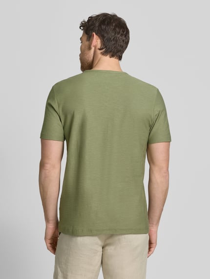 Männermodel trägt T-Shirt mit V-Ausschnitt und knoopsluiting van MCNEAL in olijfgroen, puur katoen, regular fit, ruglengte maat M 68 cm, Ganzkörperansicht Rückansicht.
