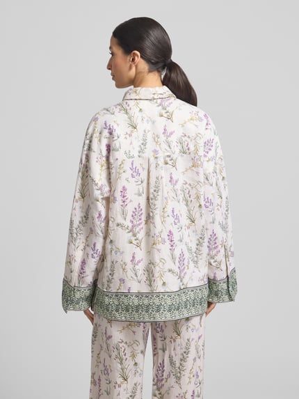 Vrouwenmodel draagt Florale Leinen Langarmbluse mit Lavendelprint van Christian Berg Woman, relaxed fit linnen blouse met bloemenmotief, overhemdkraag, ruglengte maat 36: 72 cm, mouwlengte maat 36: 49 cm, lichte tinten met lila en groene accenten, detailprint op manchetten, rugaanzicht.