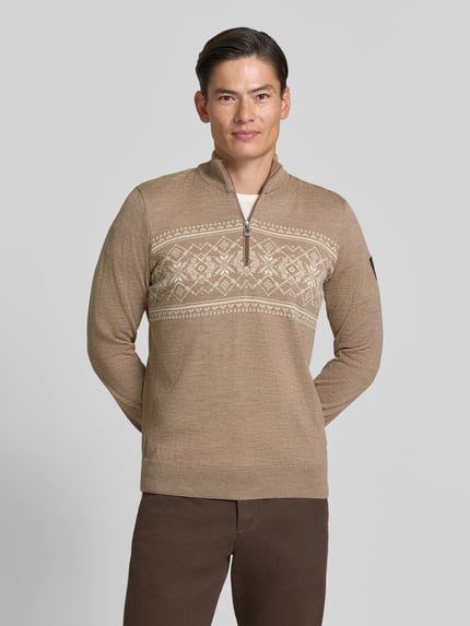 Männermodel trägt Wollpullover mit Label-Patch Modell 'Liaset' von Dale of Norway, Beige mit Norwegermuster, Nahaufnahme Oberkörper.