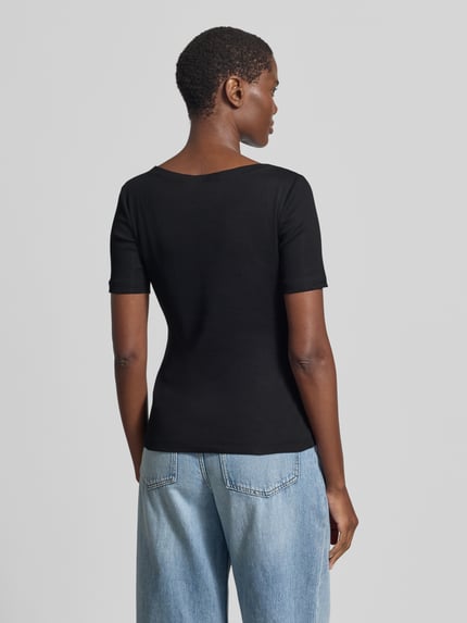 Vrouwenmodel draagt Slim Fit T-Shirt met structuurpatroon model 'Klenja' van Someday, elastische katoenmix, korte mouw, boothals, zwarte kleur, ruglengte maat 36: 56 cm, zichtbare textuur, effen design, geheel zichtbaar vanaf de achterkant.