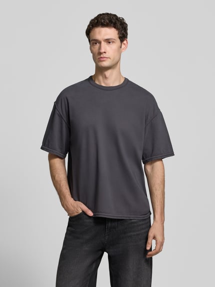 Męski model nosi T-Shirt mit Rundhalsausschnitt Modell 'FAZY' od American Vintage, czysta bawełna, krój relaxed fit, długość tyłu w rozmiarze M/L: 70 cm, widok całej sylwetki z przodu.