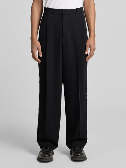 Männermodel trägt Wide Fit Hose mit Bundfalten und Schurwoll-Anteil Modell 'FEDIX' von HUGO in Two-Tone-Optik, Twill, Ganzkörperansicht von vorne.