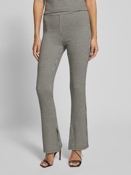 Frauenmodel trägt Slim Fit Schlaghose aus Baumwoll-Viskose-Mix Modell 'NAROSETTA' von HUGO mit Hahnentritt-Muster, High Waist, Allover-Optik, Label-Prägung und Seitenschlitz, Ganzkörperansicht von vorne.