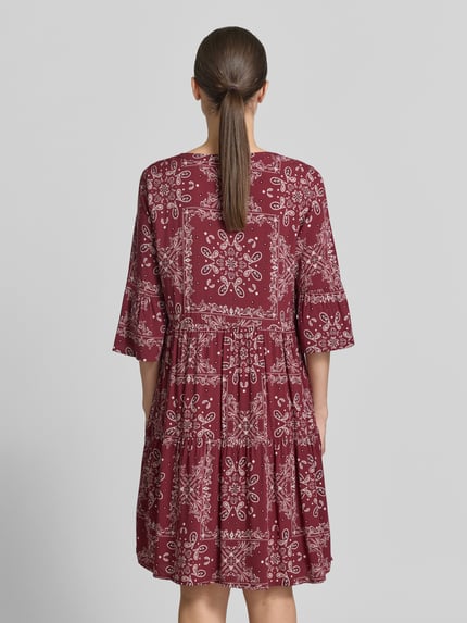 Vrouwenmodel draagt Relaxed Fit Minikleid aus reiner Viskose van Christian Berg Woman Selection, 3/4-mouw, paisleyprint, tuniekhals, effen viskose, bordeaux-witte kleuren, ruglengte 89 cm, borstwijdte 49 cm, mouwlengte 39 cm, full body achteraanzicht.