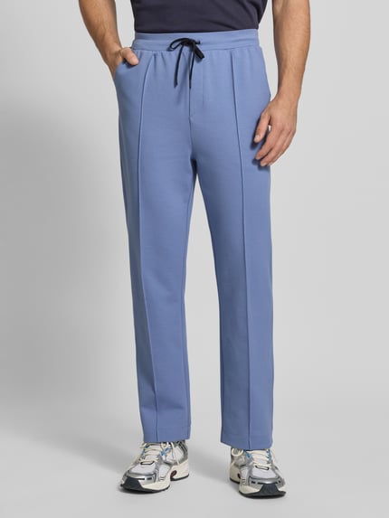Männermodel trägt Regular Fit Sweatpants aus katoenmix model 'JT_Member Hurley' van BOSS Green in effen blauw met label stitching, vaste vouw, elastische tailleband, zijzakken, sweat textuur, voorkant volledig zichtbaar, ganzkörperansicht von vorne.