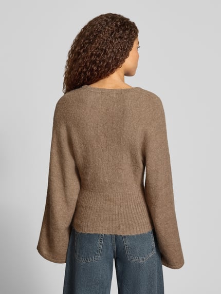 Vrouwenmodel draagt Regular Fit gebreid jack met wol van Gina Tricot in bruin, elastische materiaalmix, ribboorden, lange mouwen, ruglengte maat S 53 cm, mouwlengte maat S 49 cm, productfoto, geheellichaamsaanzicht achteraan.