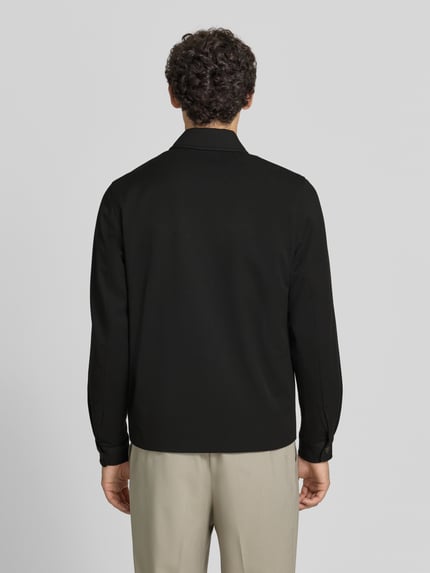 Männermodel trägt Jacke mit Logo-Stitching Modell 'Como' von Les Deux in Schwarz, gerade Passform, Rückansicht, Material-Mix mit Viskose-Anteil.