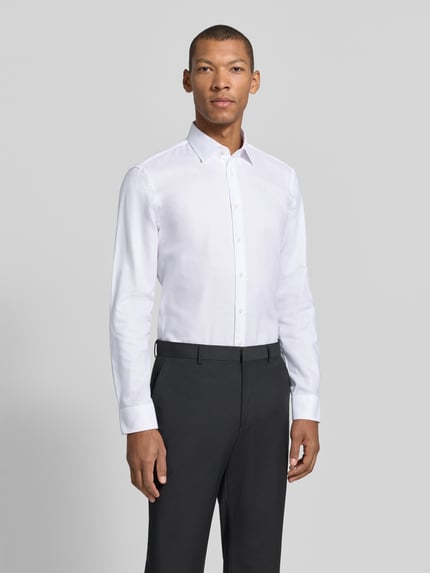Männermodel trägt Slim Fit Businesshemd aus reiner Baumwolle von JAKE*S, weiß, feines Webmuster, Ganzkörperansicht von vorne.