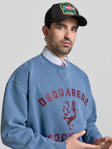 Männermodel trägt Regular Fit Sweatshirt mit Logo-Detail von Dsquared2 in Blau, reine Baumwolle, Rundhalsausschnitt, Nahaufnahme Oberkörper.
