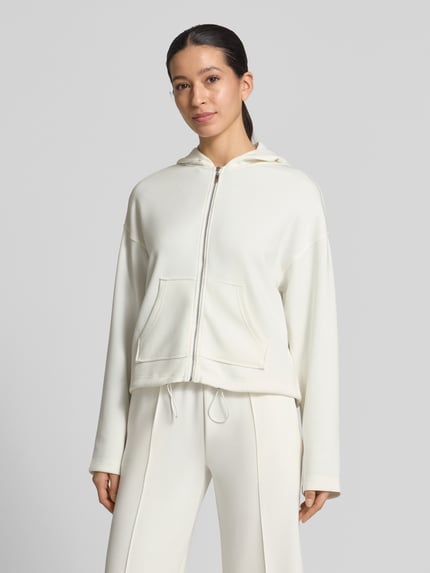 Vrouwenmodel draagt Regular fit sweatjacke met kapuze Modell 'Marcella' van Christian Berg Woman in crème, elastische materiaalmix met modal, kangoeroezak en trekkoordzoom. Vooraanzicht, bovenlichaam close-up.