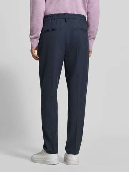Männermodel trägt Stoffhose mit Bügelfalte Modell 'MARC' von Casual Friday in Dunkelblau, Material-Mix, elastischer Bund, Ganzkörperansicht Rückansicht.