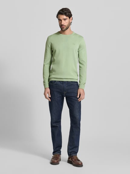 Männermodel trägt Regular Fit Pullover aus reiner Baumwolle von s.Oliver RED LABEL in hellem Melangegrün, Feinstrick, Rundhals, Ganzkörperansicht von vorne.