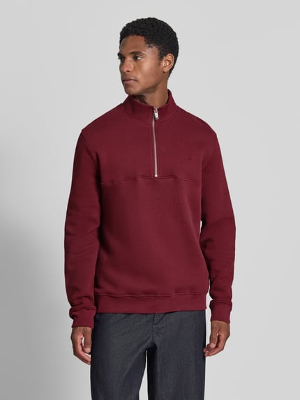 Männermodel trägt Regular Fit Troyer aus reiner Baumwolle Modell 'WAARLO' von ARMEDANGELS in Dunkelrot, glatte Textur, Ganzkörperansicht von vorne.