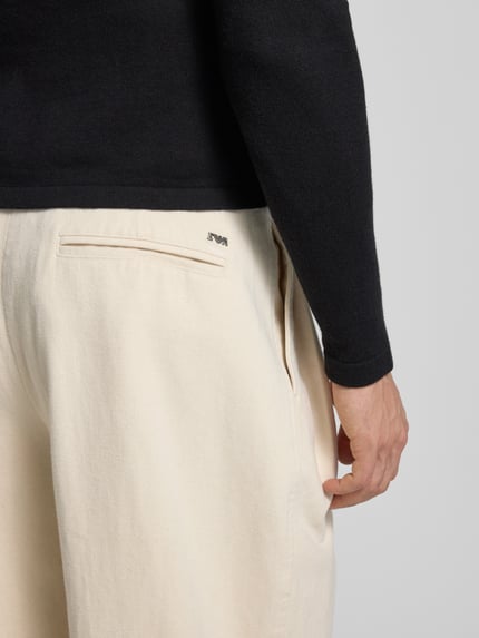 Männermodel trägt Stoffhose mit französischen Eingrifftaschen von Emporio Armani, Reine Baumwolle, Gerader Schnitt, Detailaufnahme Rückansicht.