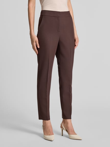 Frauenmodel trägt Regular Fit Anzughose mit elastischem Bund von s.Oliver BLACK LABEL in dunkelbraun, glatte Struktur, Nahaufnahme Oberkörper.