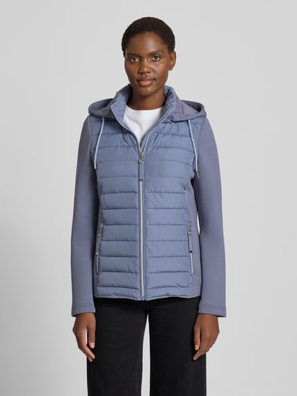 Frauenmodel trägt Steppjacke mit Kapuze und Reißverschlusstaschen von Christian Berg Woman Selection, hellblau, Regular Fit, glatte und gesteppte Texturen, Reißverschluss und seitliche Reißverschlusstaschen, Ganzkörperansicht von vorne. Rückenlänge 59 cm, Schulterbreite 41 cm, Brustweite 50 cm, Ärmellänge 65 cm bei Größe 36.
